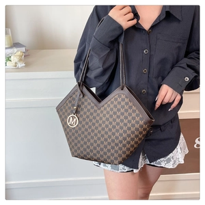 Détail d'un sac seau marron à motif M avec une coupe en V et un pendentif en métal