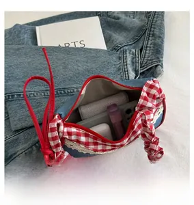 Detail view of denim handbag interior holding mobile phone, earphones and lipstick