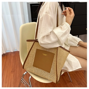 Detailed view of straw woven tote bag featuring brown leather trim and shoulder straps
