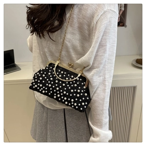 Detail of elegant black lace evening bag with white pearl accents and gold chain strap