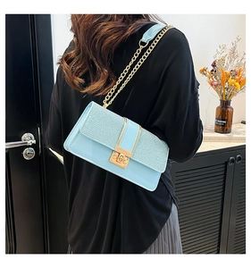 Detailed close-up of light blue patchwork handbag with gold chain and metal lock