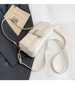 Detail of a creamy beige leather crossbody bag featuring a classic gold metal buckle closure