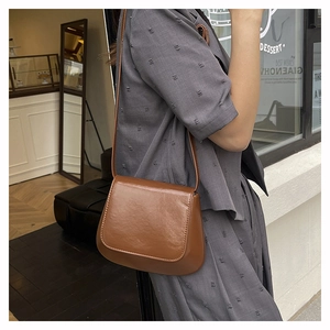 Stylish brown retro saddle crossbody bag for women shown in a casual street setting