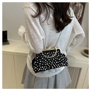 Detail of elegant black fabric clutch with white pearls and gold metal chain strap