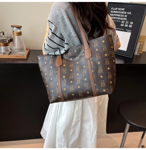 Detail of large brown tote bag with bear pattern and rhombus print worn in a cafe setting