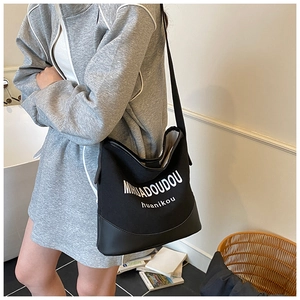 Détail du sac fourre-tout en toile noire avec fond en cuir et lettres brodées blanches