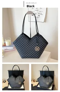 Detail of a monogrammed black and grey tote bag with gold M-shaped pendant and thin straps