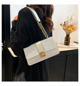 Close-up of stylish white sequined crossbody bag with silver accents and golden chain strap