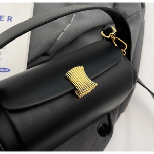 Detail of black semi-cylindrical leather bag featuring gold vertical fan-shaped metal buckle