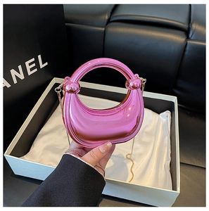 Close-up of metallic pink half-moon acrylic clutch with gold chain and round handle