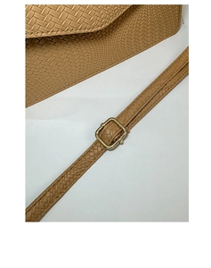 Gros plan sur la texture tressée et la boucle dorée d'un sac à bandoulière kaki élégant.