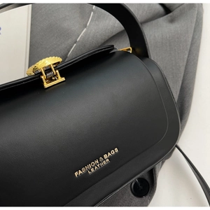 Close-up of black leather handbag with gold metal lock and elegant logo text detail