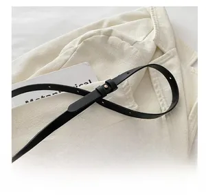 Detail of adjustable black leather shoulder strap with gold buckle and multiple punch holes