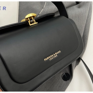 Close-up of black leather crossbody bag featuring a unique fan-shaped gold metal lock