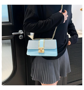Detail of light blue denim patchwork bag with gold metal chain and rotary lock buckle