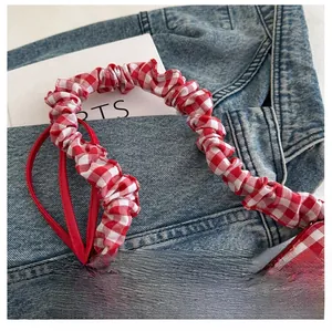 Detail of red and white plaid elastic ruffled shoulder strap on denim background