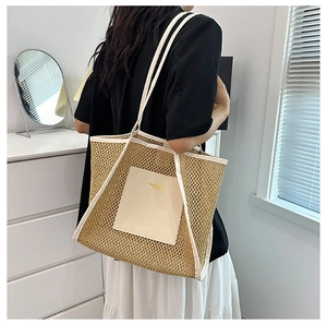 Detail of a woven straw tote bag featuring white leather trim and side shoulder strap