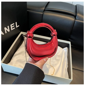 Detail view of mini red crescent moon bag with circular handle and glossy mirror finish