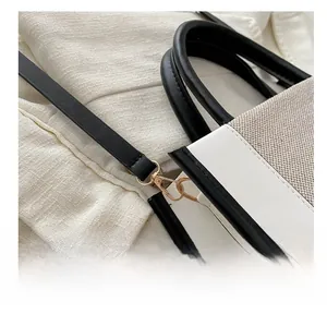 Detail of the golden metal hook and black leather strap on a canvas crossbody bag