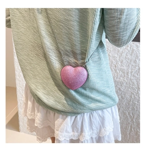 Dettaglio della mini borsa a cuore glitter rosa con sottile tracolla a catena argentata