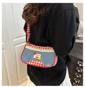 Detail of denim shoulder bag with red gingham trim and sweet cherry patch embroidery