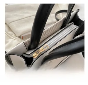 Detail of contrast shoulder bag featuring smooth gold zipper and black leather trim