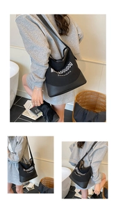 Détail du sac seau en toile noire avec logo blanc et bandoulière en cuir réglable