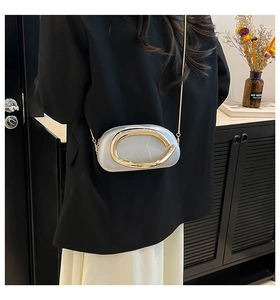 Back view of model wearing small silver oval crossbody bag with gold chain and large buckle