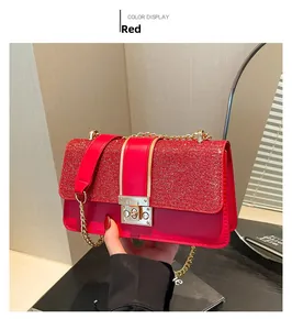 Detail of red glitter crossbody bag with gold chain strap and turn-lock closure