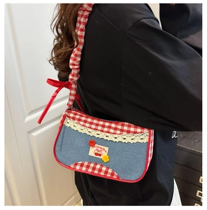 Detail of checkered tote bag with lace trim, cherry patch, and red ribbon bow accent