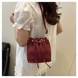 Detail view of burgundy faux suede bucket bag with drawstring and metallic eyelets