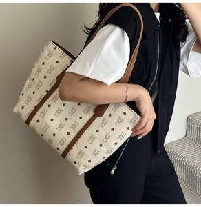 Detail of cream tote bag with bear print patterns and brown leather strap accents
