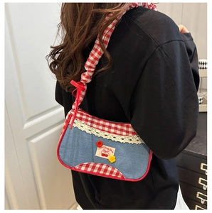 Detail of blue denim shoulder bag with red gingham trim and cherry patch detail