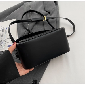 Detail of minimalist black crossbody square bag with golden buckle and matte leather