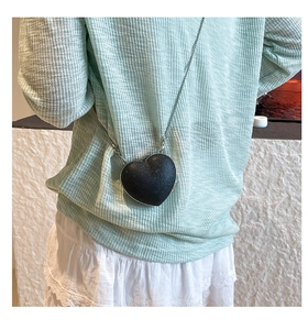 Dettaglio di una mini borsa a tracolla a cuore nera con paillettes e catena argento