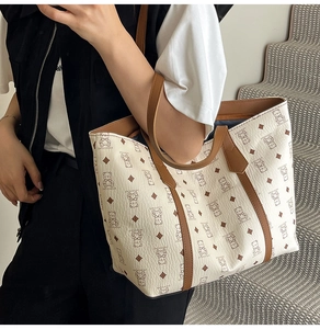 Detail of a large white tote bag with bear print, brown leather handles, and spacious interior
