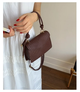 Gros plan montrant le motif tissé complexe et le design du sac à main marron carré