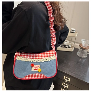 Detailed shot of cherry patchwork denim shoulder bag with red plaid and lace trim