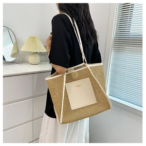 Detail of woven straw tote bag featuring white leather handles and gold fashion lettering