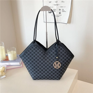Sac fourre-tout vintage à motif M, ouverture en V et pendentif doré sur surface blanche