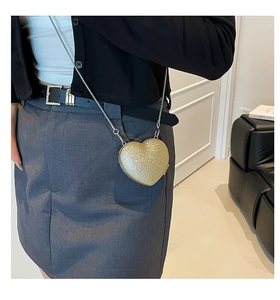 Dettaglio di borsa da sera a cuore con paillettes dorate e tracolla a catena argento