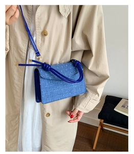 Detailed view of a stylish blue denim textured small square crossbody bag worn by a model