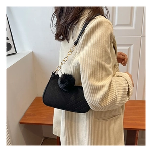 Detailed shot of a vintage black square shoulder bag with a soft pom-pom charm