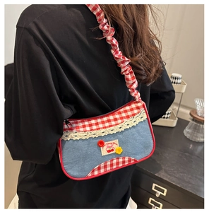 Detailed view of the denim bag with red plaid trim, lace edges, and floral button accents
