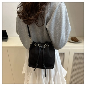 Detailed view of black matte bucket bag with drawstring closure and golden hardware detail