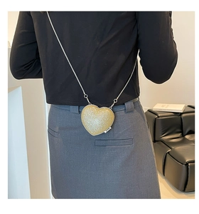 Dettaglio mini borsa a tracolla a forma di cuore con paillettes dorate e catena d'argento