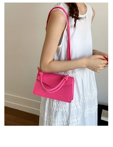 Vue détaillée du sac à main rose élégant à texture tissée avec poignée nouée sur modèle