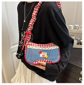 Close-up of blue denim and red plaid fabric bag with lace and cherry patch details