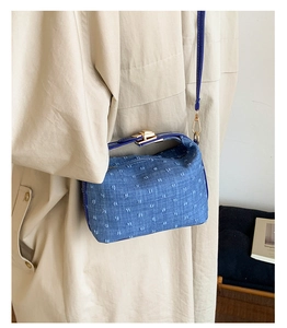 Close-up detail of a blue vintage-style ingot-shaped shoulder bag worn on shoulder