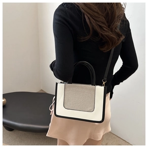 Minimalist bicolor tote bag with contrasting textures worn as a crossbody by a model
